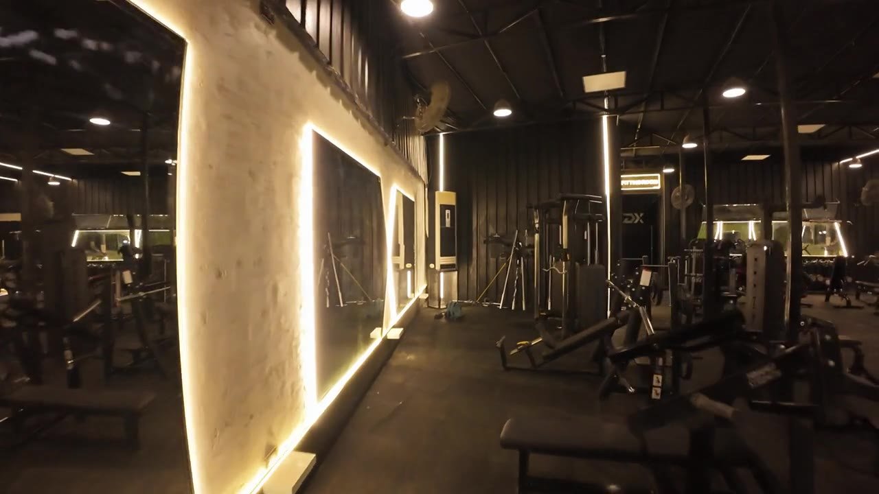 The chest machine area under a warm backlit feature wall.